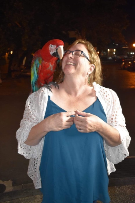 Kris smiling with a parrot during her travels